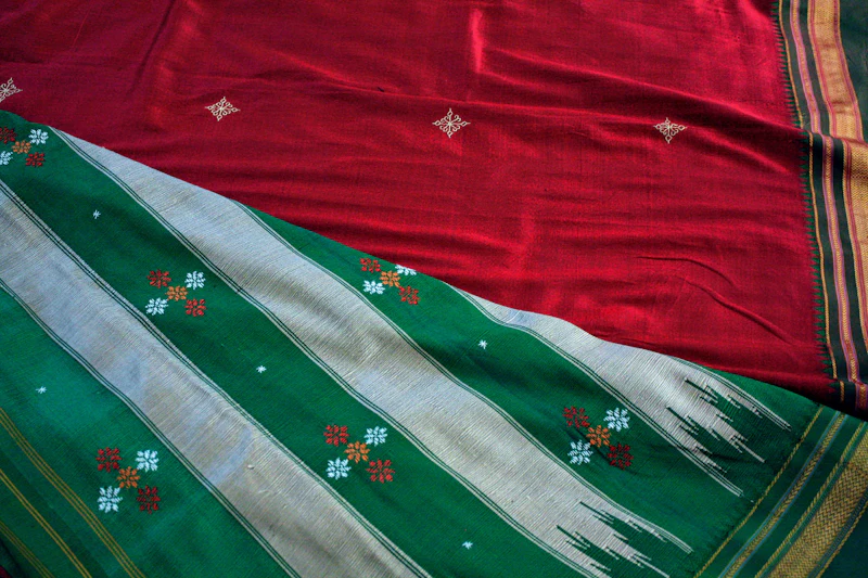 Detail of a red and green saree with woven borders and small decorative motifs